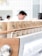 Paper coffee cups with a minimalist design featuring a percentage symbol on them are neatly arranged in rows atop a modern espresso machine. The background shows blurred figures, likely baristas, in a clean, bright cafe setting.