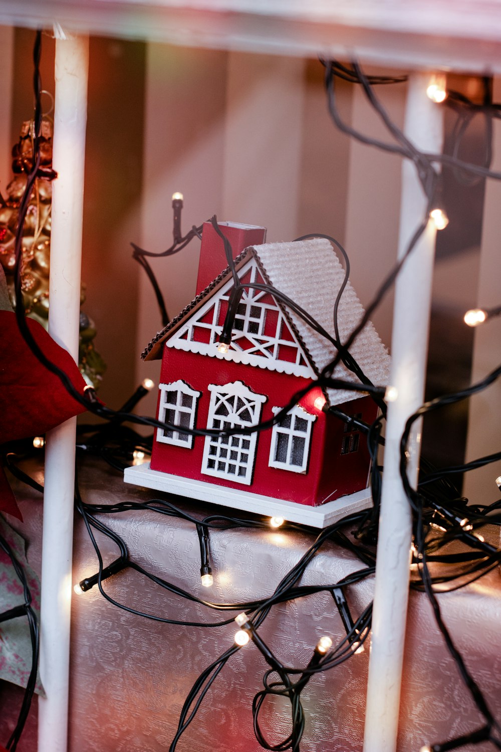 a red house with a white roof is surrounded by christmas lights