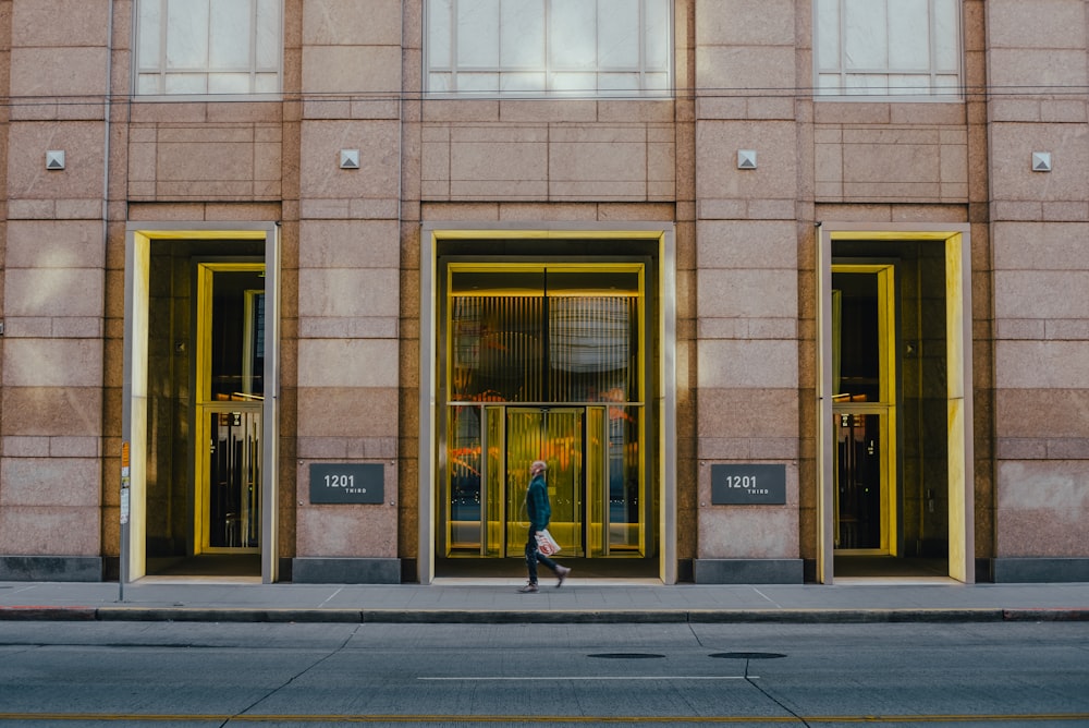 a person walking past a tall building with yellow doors