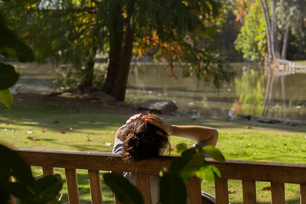 a woman sitting on a wooden bench in a park