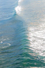 Close-up of hands touching gentle ocean waves under bright sunlight