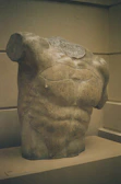 Elegant black and beige sculpture inspired by ancient Greek forms displayed on a pedestal.