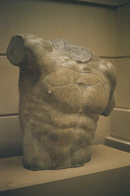 Elegant black and beige sculpture inspired by ancient Greek forms displayed on a pedestal.