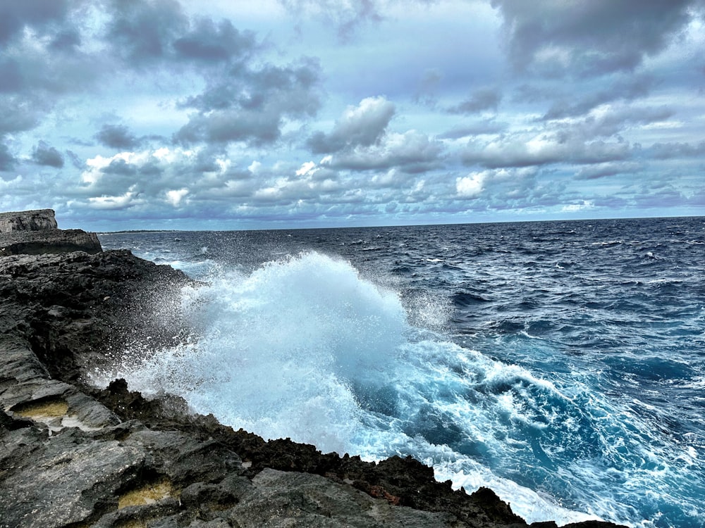 a large wave crashing into the rocks near the ocean