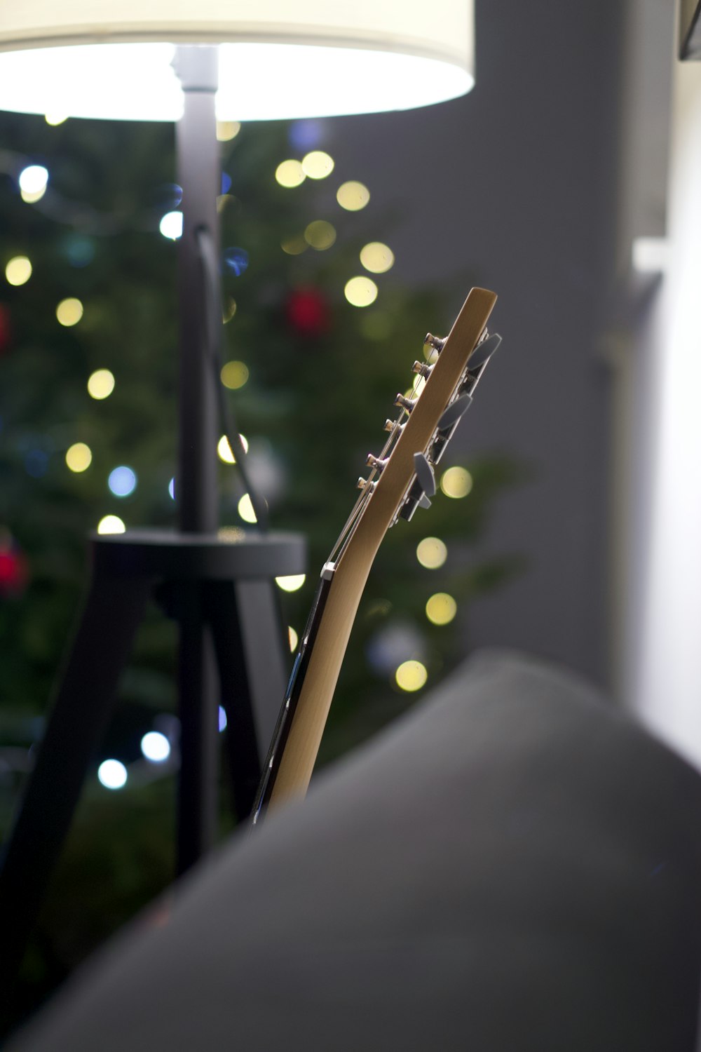 a close up of a guitar near a christmas tree