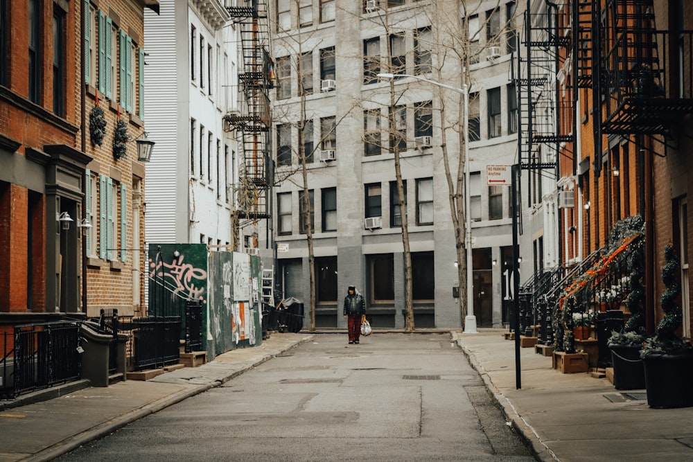 a man walking down a street next to tall buildings