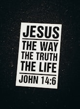 A black and white poster with a religious message. The text reads 'Jesus The Way The Truth The Life' followed by the Bible reference 'John 14:6'. The poster is set against a dark background.