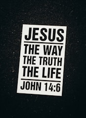 A black and white poster with a religious message. The text reads 'Jesus The Way The Truth The Life' followed by the Bible reference 'John 14:6'. The poster is set against a dark background.