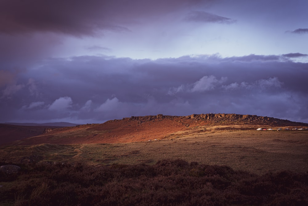 a hill with a small house on it under a cloudy sky