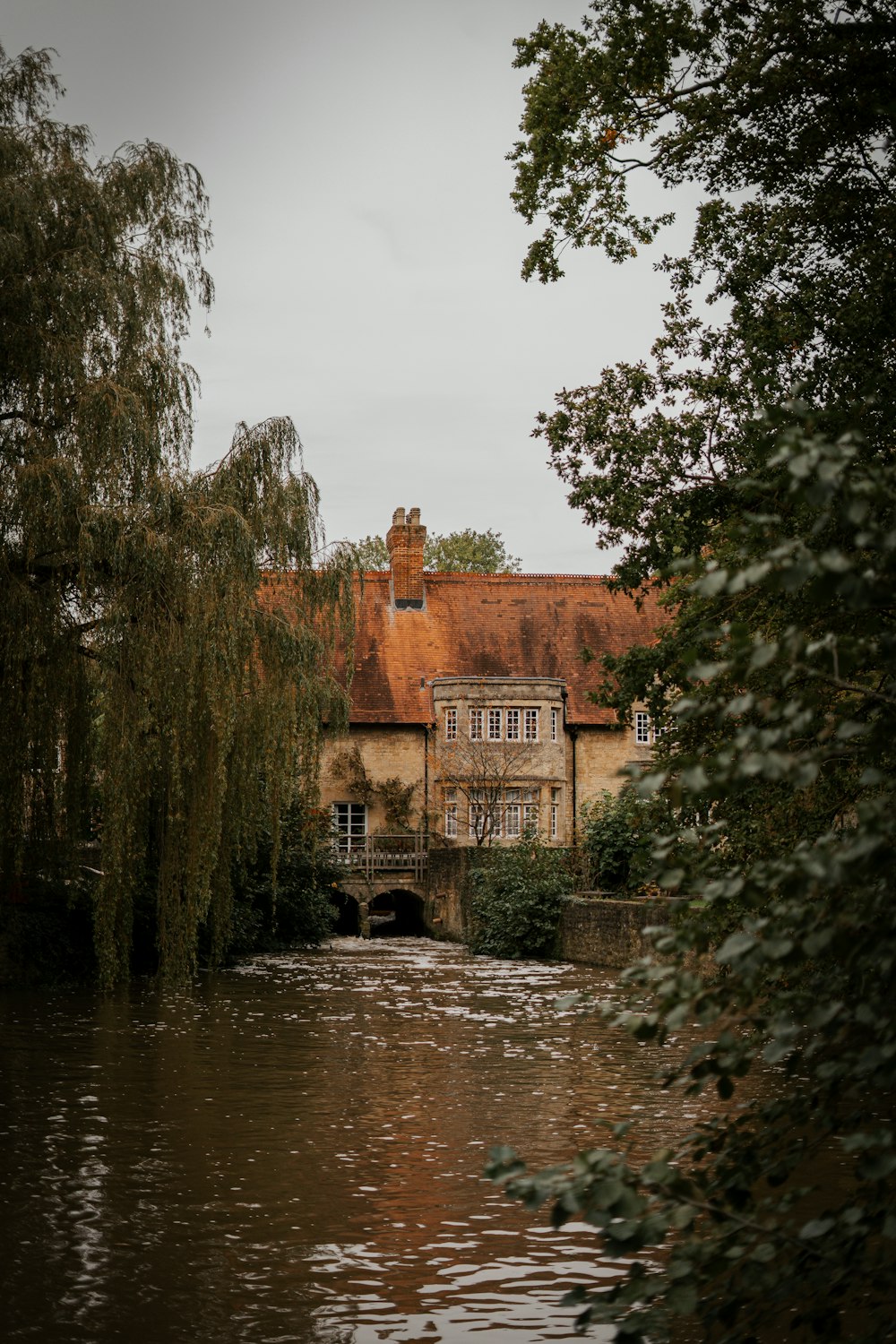 a house sitting on top of a river next to a lush green forest