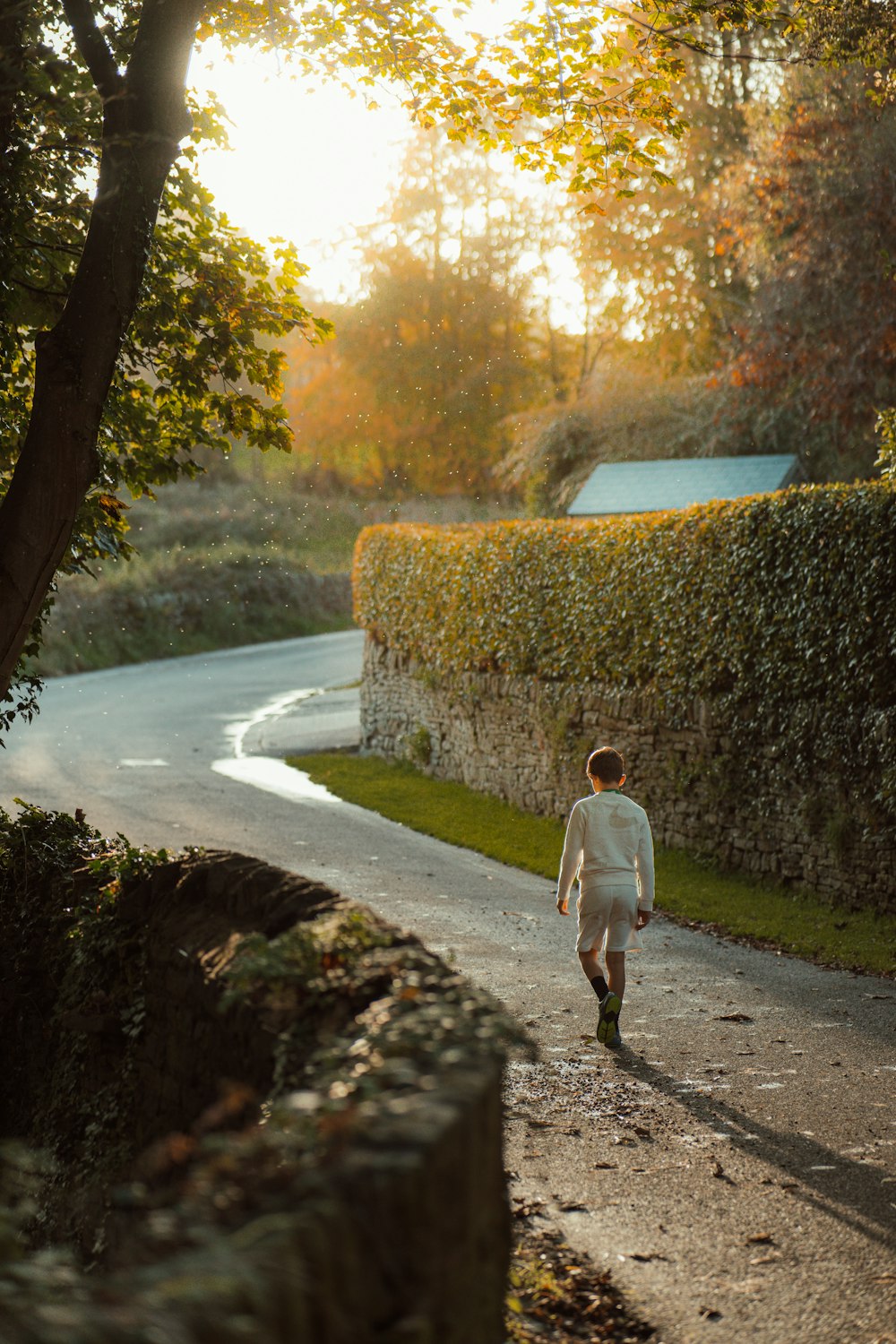 a man walking down a road next to a lush green forest