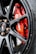 A close-up shot of a red Brembo brake caliper mounted on a dark alloy wheel of a vehicle. The metallic surface of the wheel complements the vibrant red of the caliper, which bears the white Brembo logo. The background shows part of the brake disc.