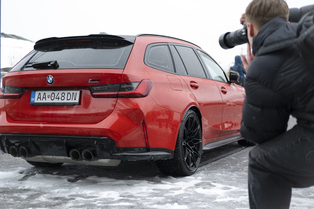 a man taking a picture of a red car