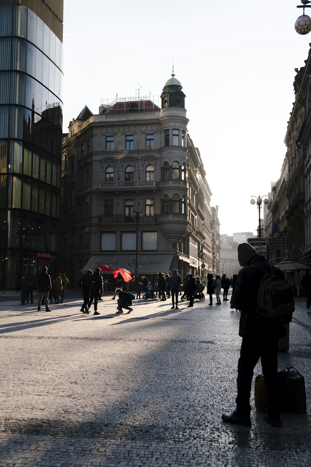 a man with a red umbrella standing in the middle of a street