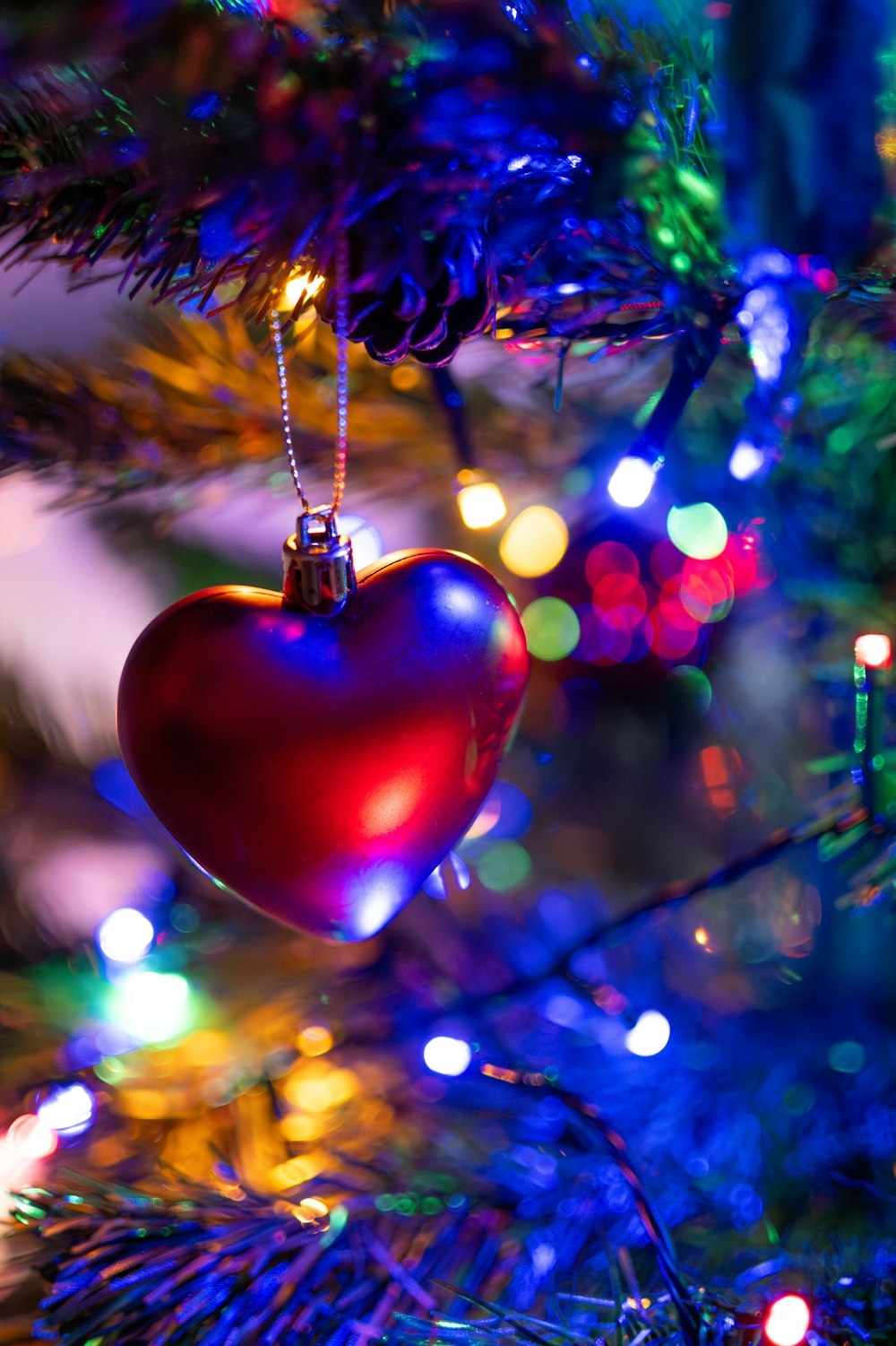 a red heart ornament hanging from a christmas tree