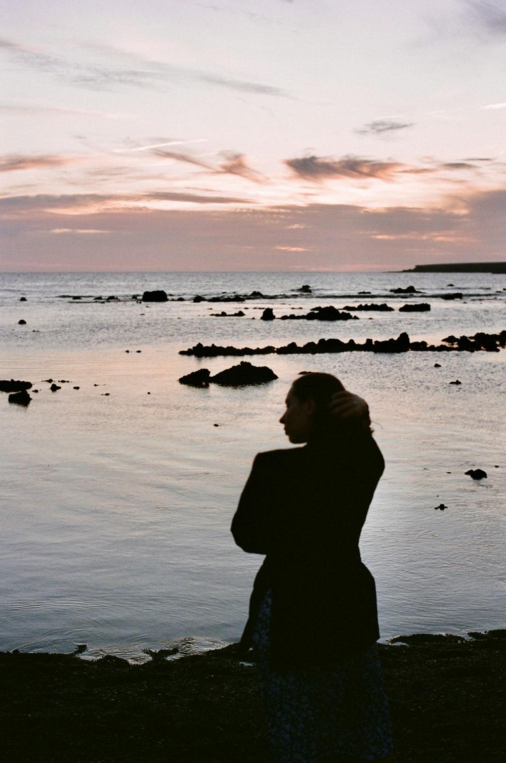 a woman standing on a beach next to a body of water