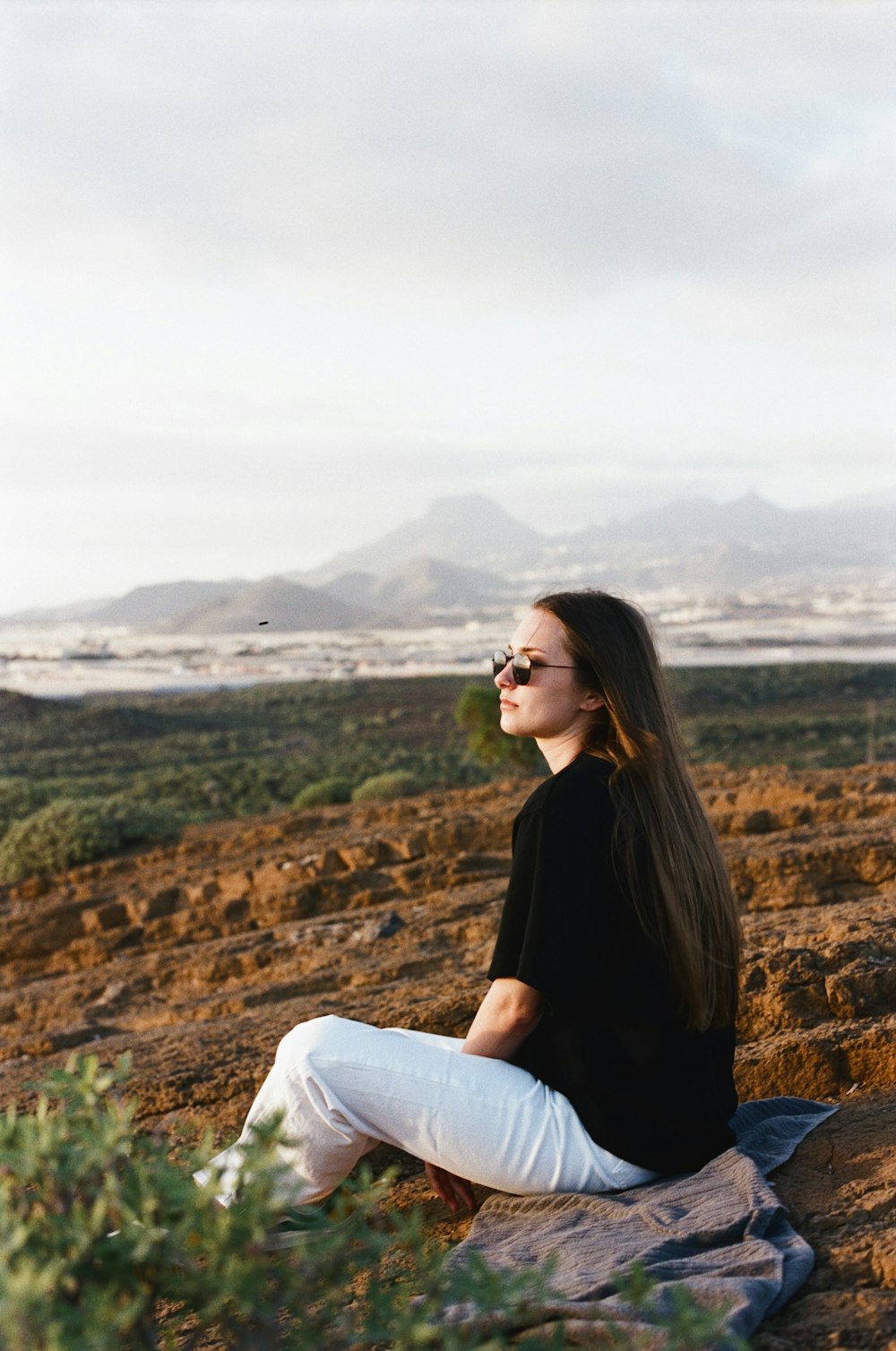 a woman sitting on a blanket in the desert