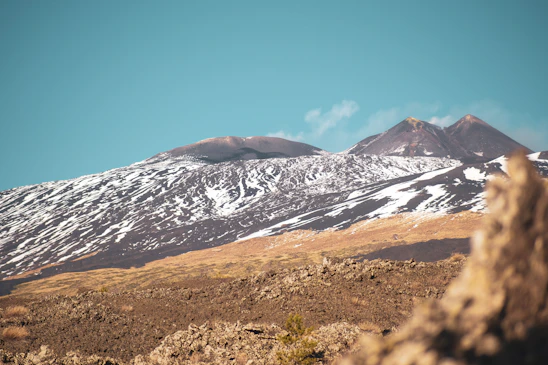 Snow-capped peak of Nevado de Toluca volcano under a clear sky, surrounded by rugged mountain terrain.