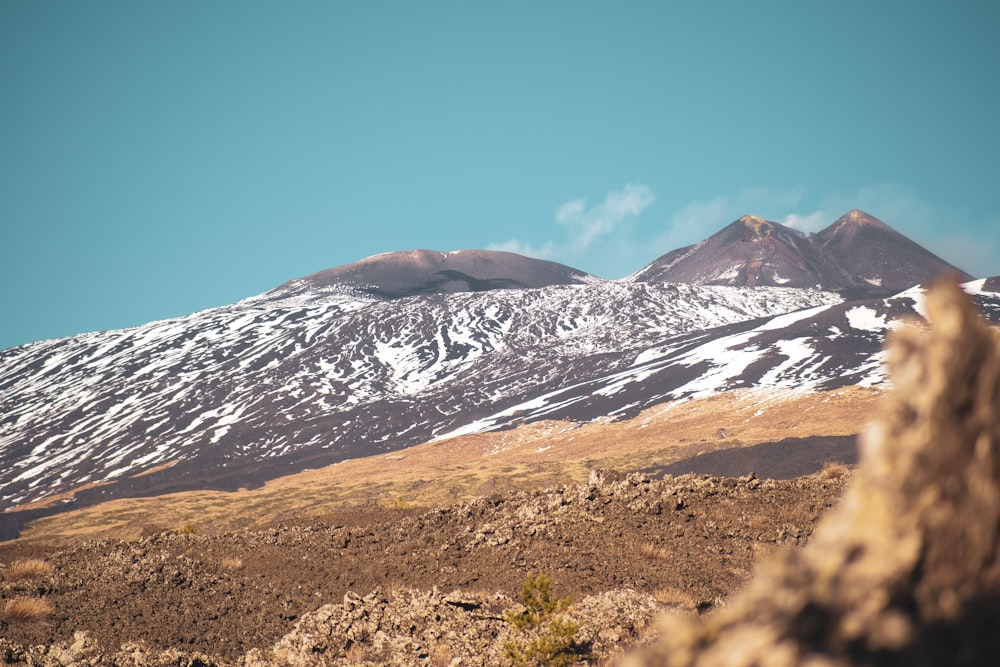 a snow covered mountain with a rock outcropping in the foreground