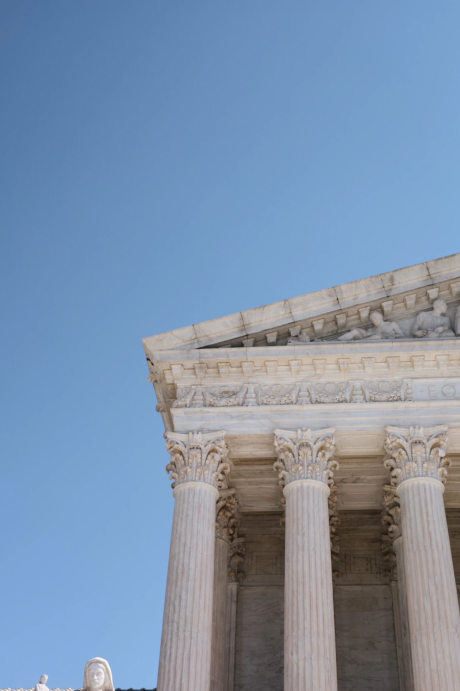 White marble columns of a courthouse beneath a clear sky