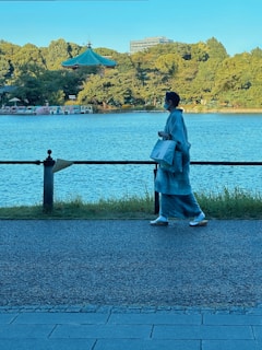 A customer carrying a bamboo origin handbag while walking through a sunny park.