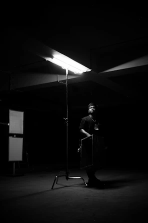 Silhouette of a lone man standing strong in a dark, minimalist room with sharp shadows.
