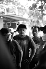 A group of friends smiling and dancing together outdoors wearing wireless headphones.