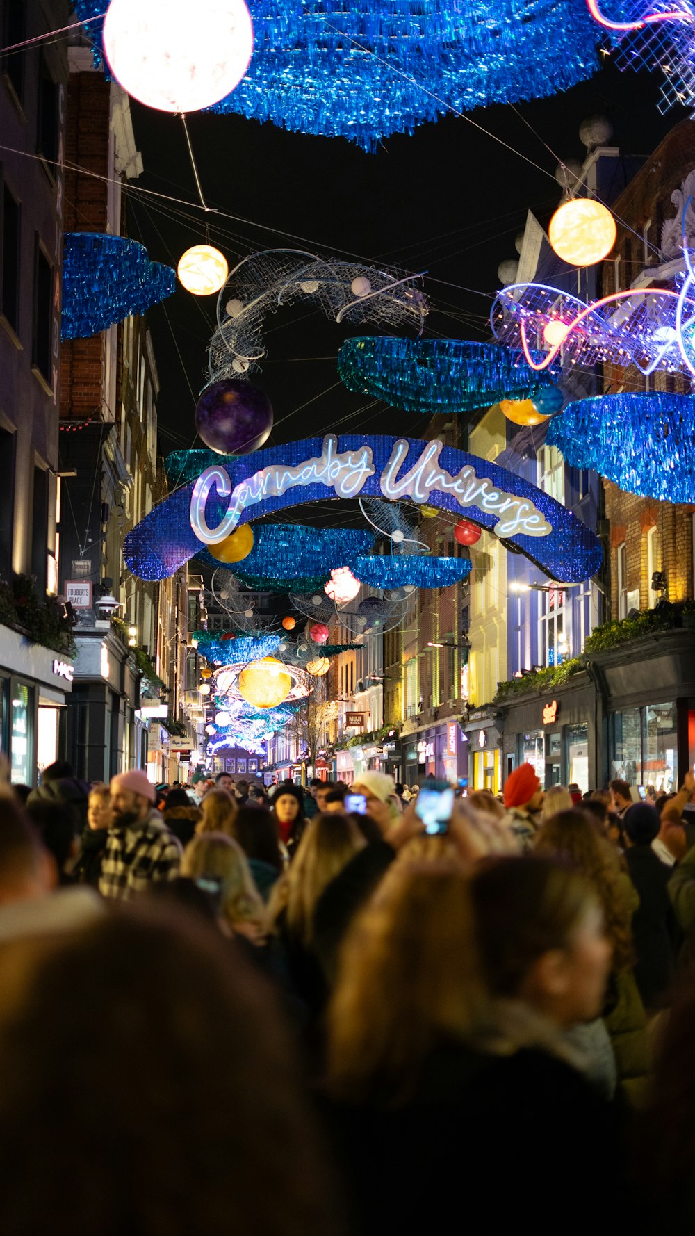 a crowd of people walking down a street at night