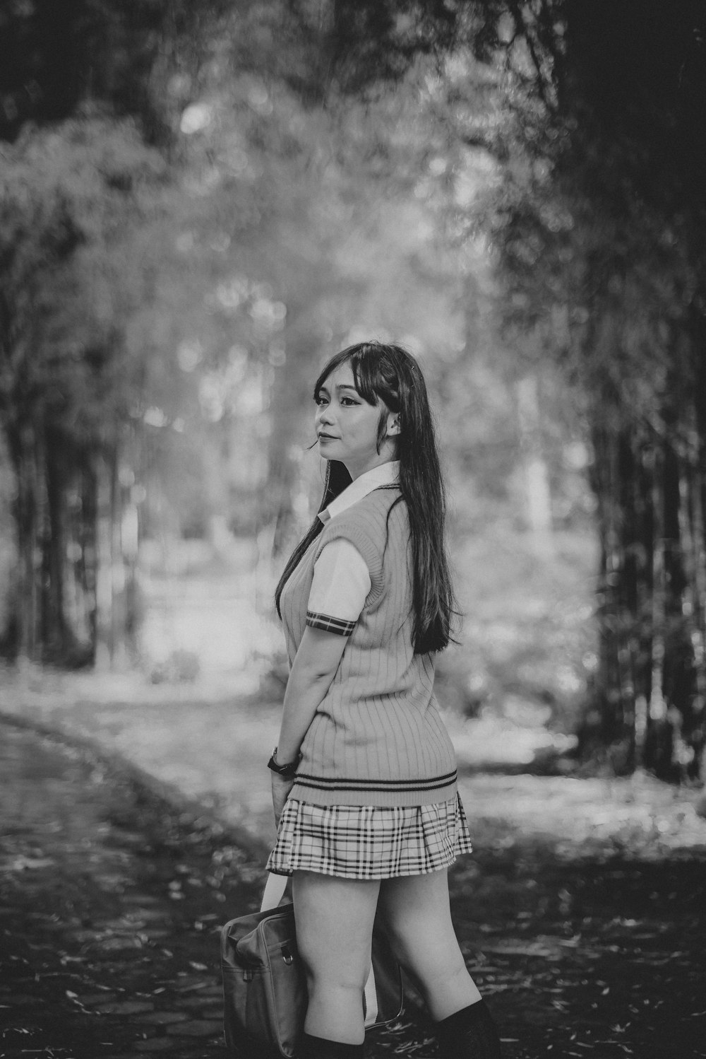 a woman standing in the woods talking on a cell phone