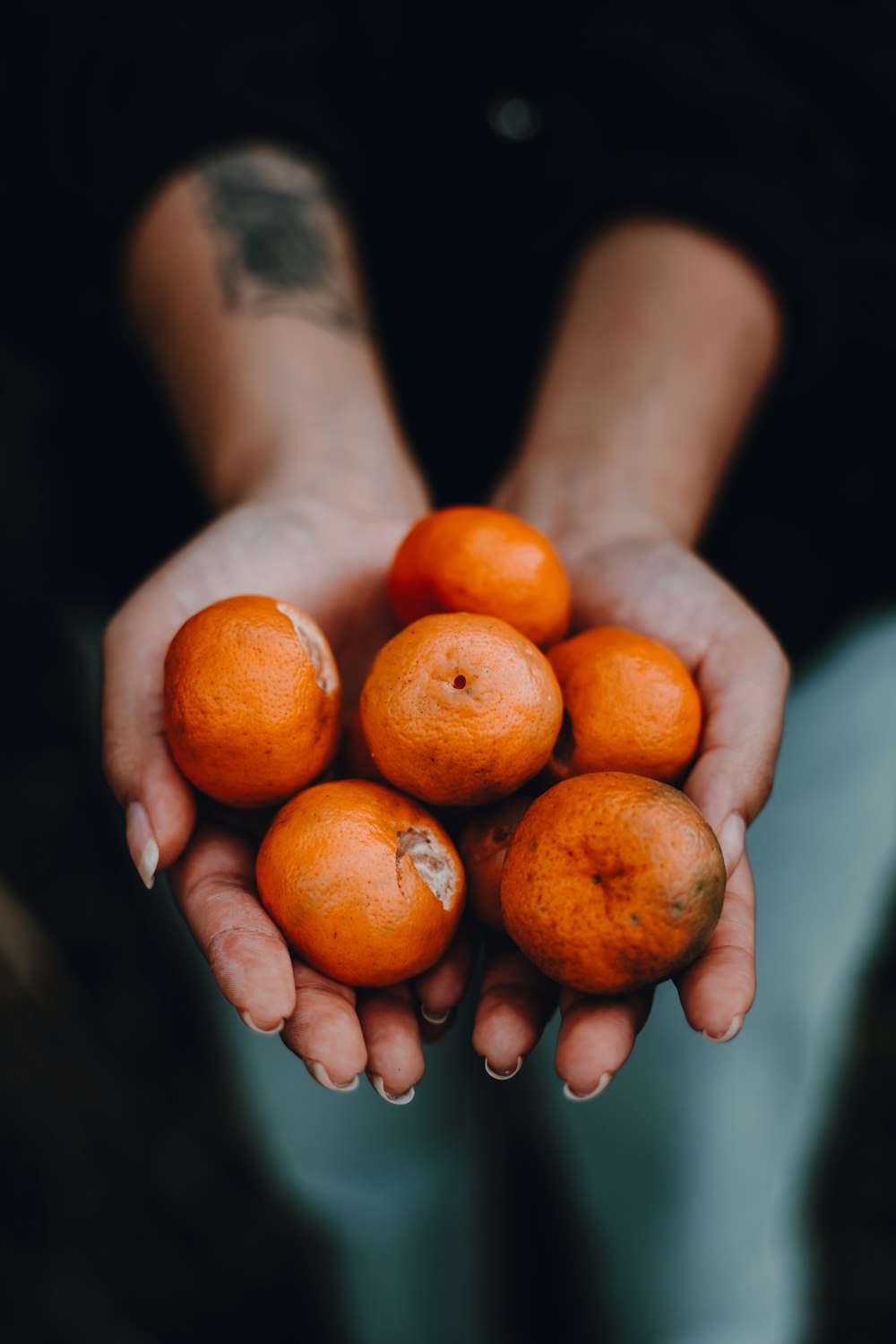 a person holding a handful of oranges in their hands