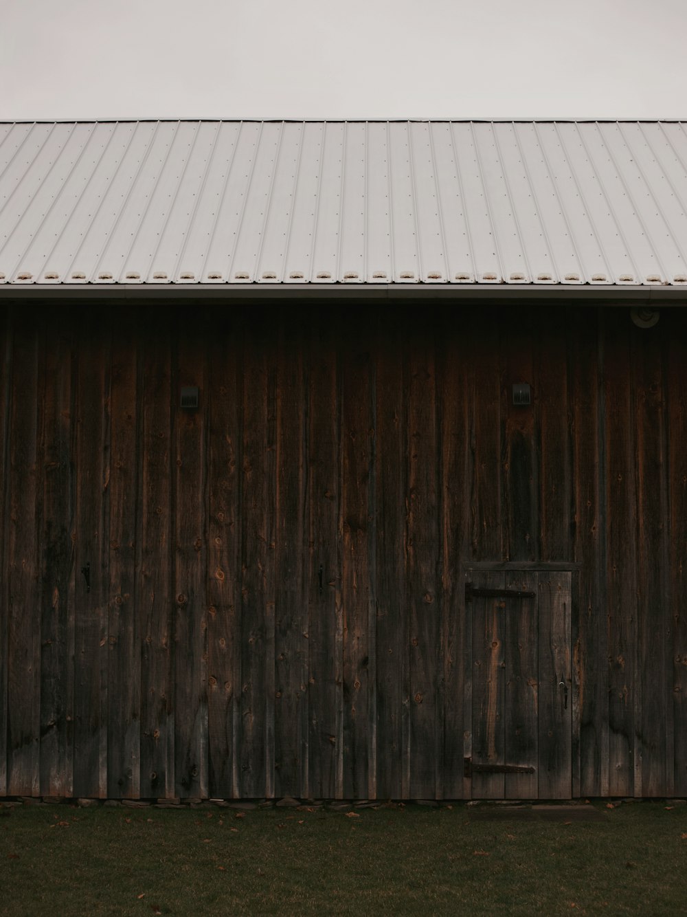 a barn with a metal roof and a wooden door