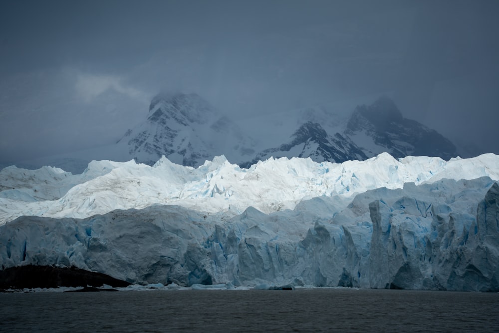 a large glacier with mountains in the background