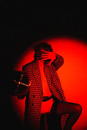 a man in a checkered coat is covering his face with his hands