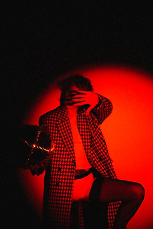 a man in a checkered coat is covering his face with his hands