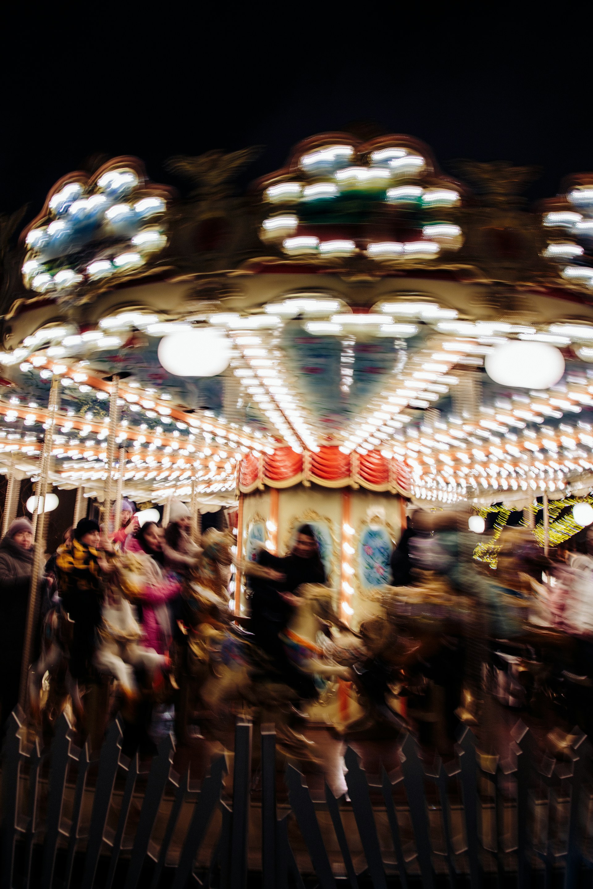 A vibrant carousel photo with colorful lights blurred in the background at dusk.
