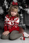 a little girl sitting in front of a christmas tree
