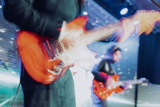 Close-up of young musicians playing electric guitars with fierce expressions.