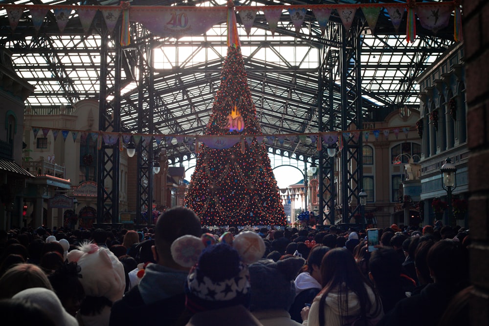 a large christmas tree is in the middle of a crowd