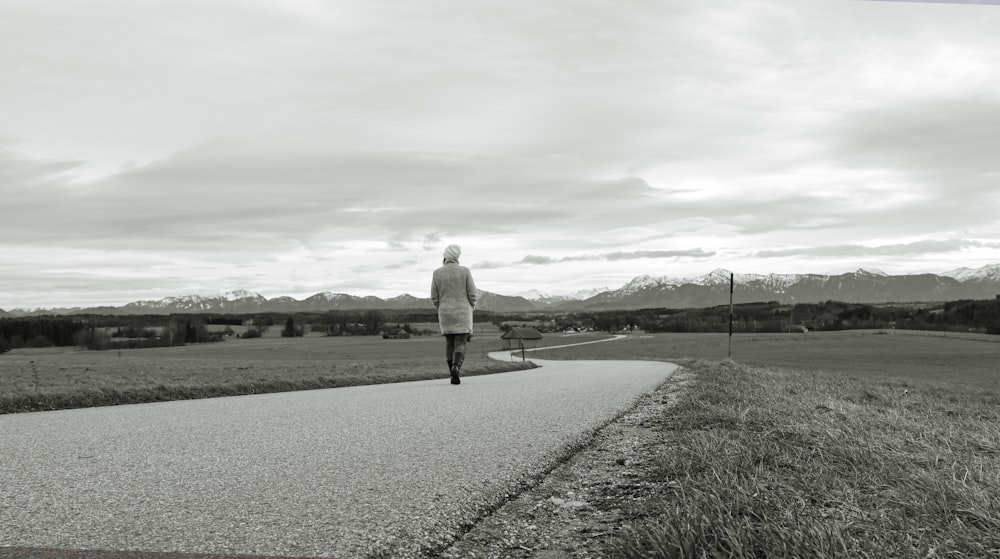 a person walking down a road in a black and white photo