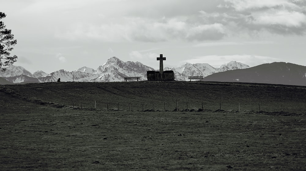 a black and white photo of a cross on a hill