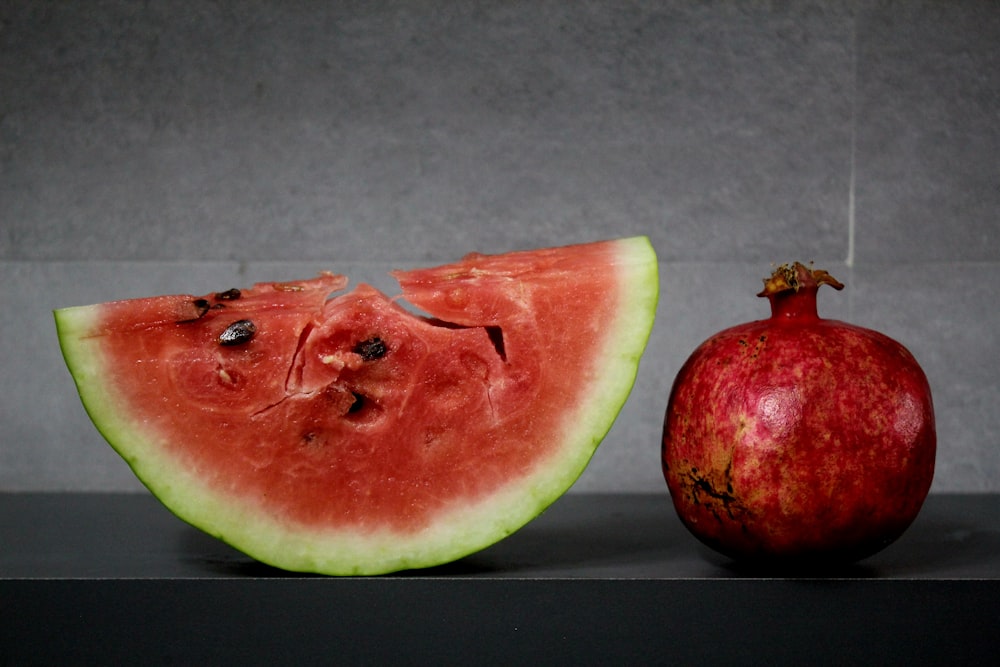 a slice of watermelon next to an apple