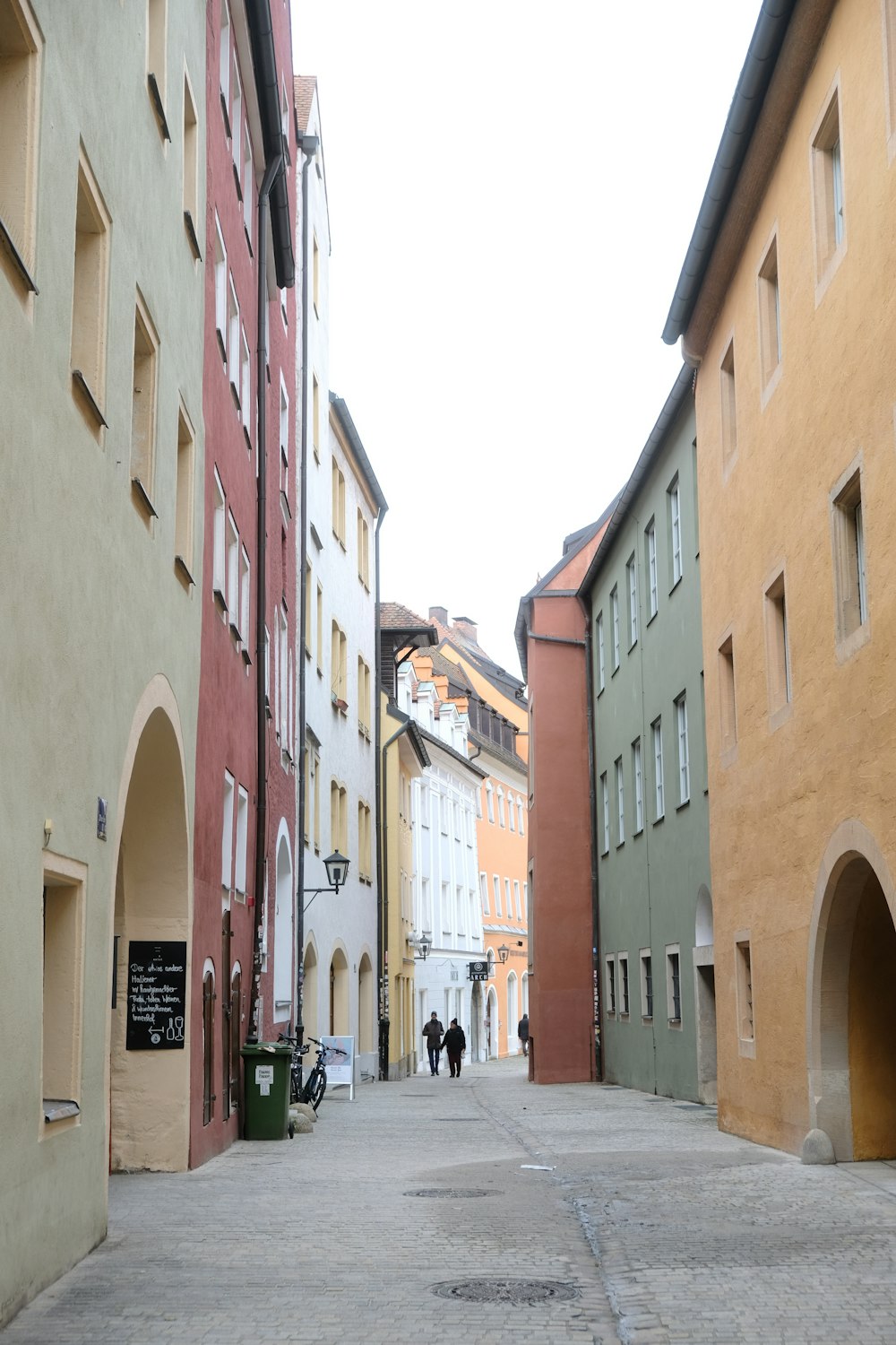 a couple of people walking down a street next to tall buildings