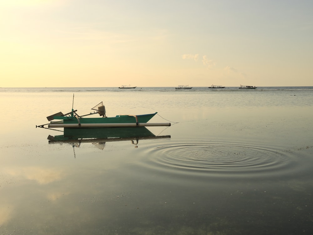 a small green boat floating on top of a lake