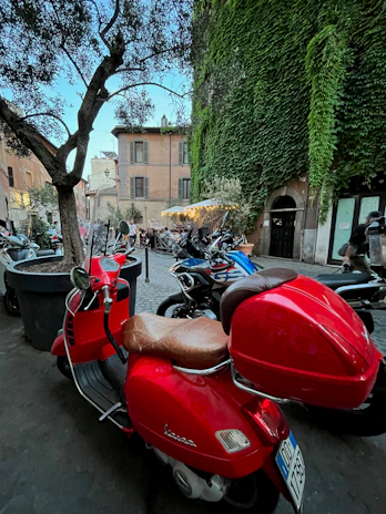 A bright red scooter on a cobblestone street lined with colorful Italian buildings