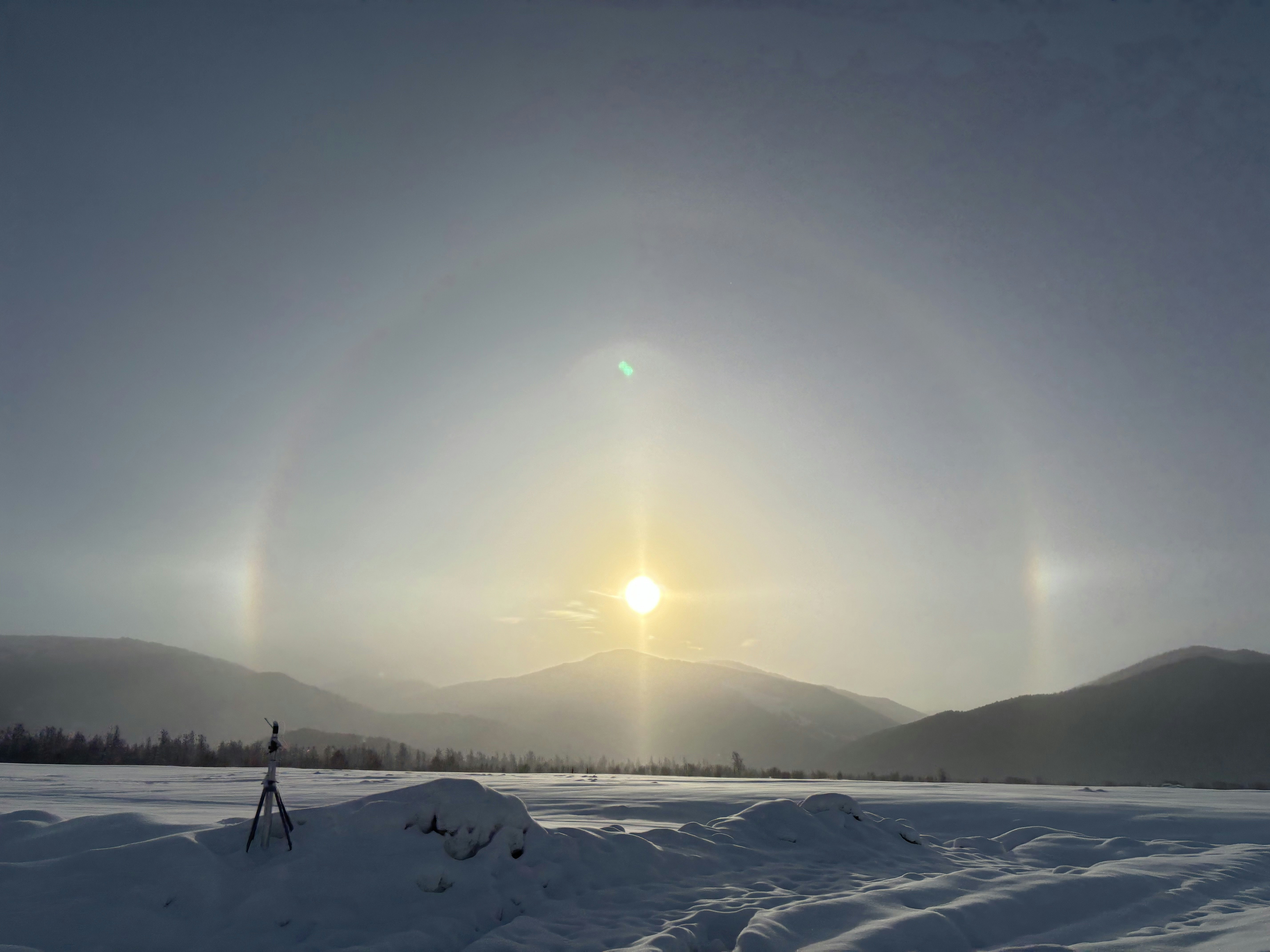 the sun is setting over a snowy field