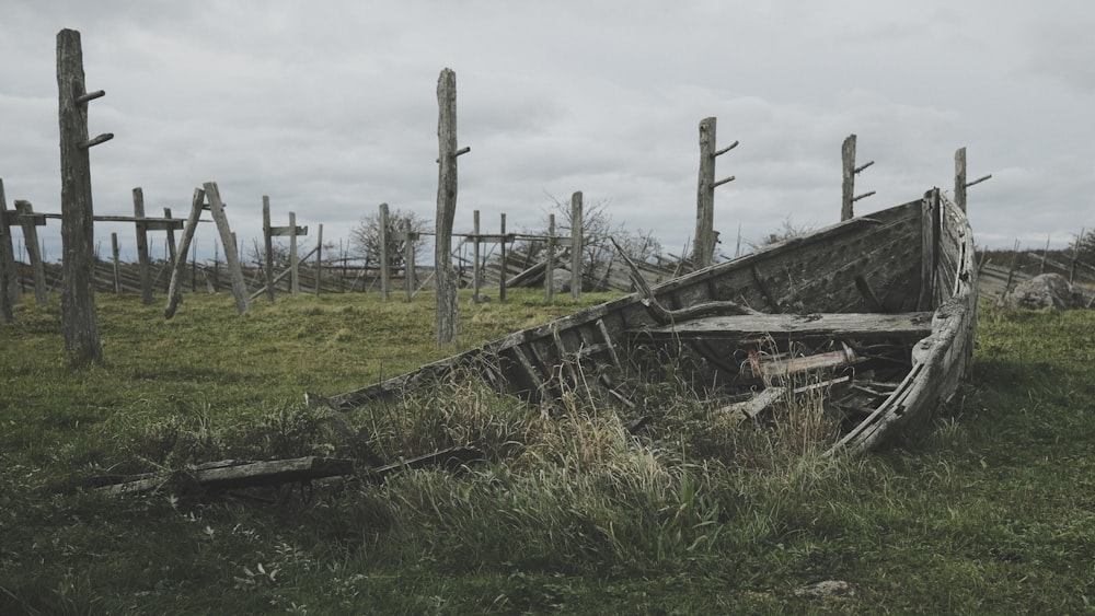 an old wooden boat sitting on top of a lush green field