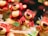 Several plush toy bears with cheerful expressions, featuring red and yellow colors, are arranged in a playful manner. Some are standing, while others appear relaxed in various poses. The background is softly blurred, emphasizing the bears.