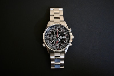 a watch sitting on top of a metal bracelet