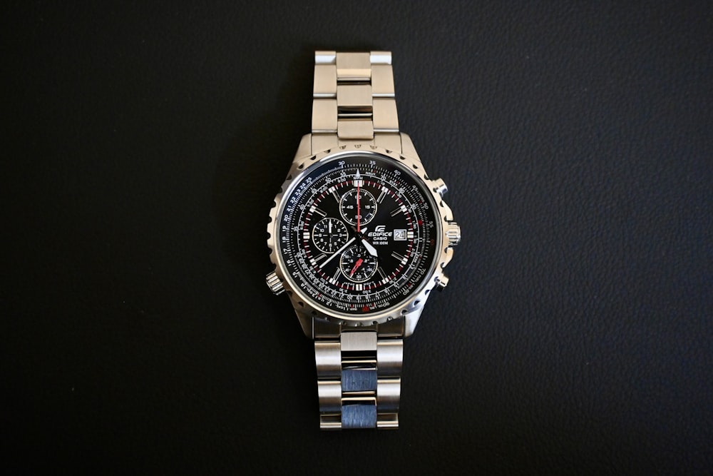 a watch sitting on top of a metal bracelet