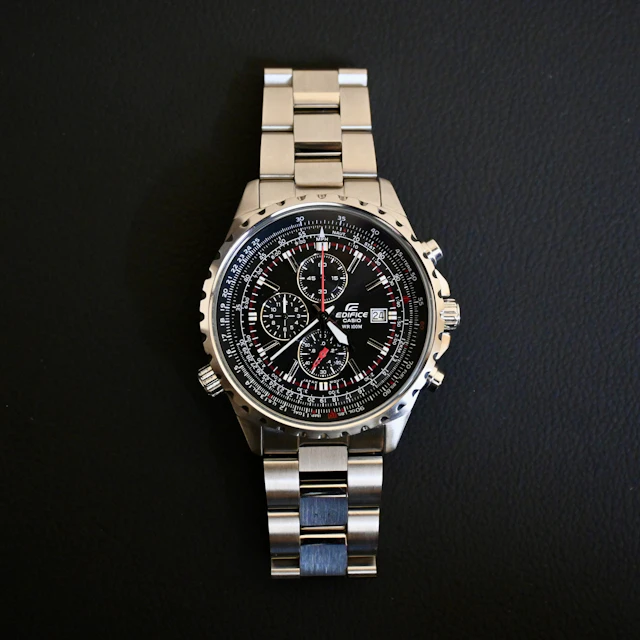 A wristwatch resting on top of a metal link bracelet